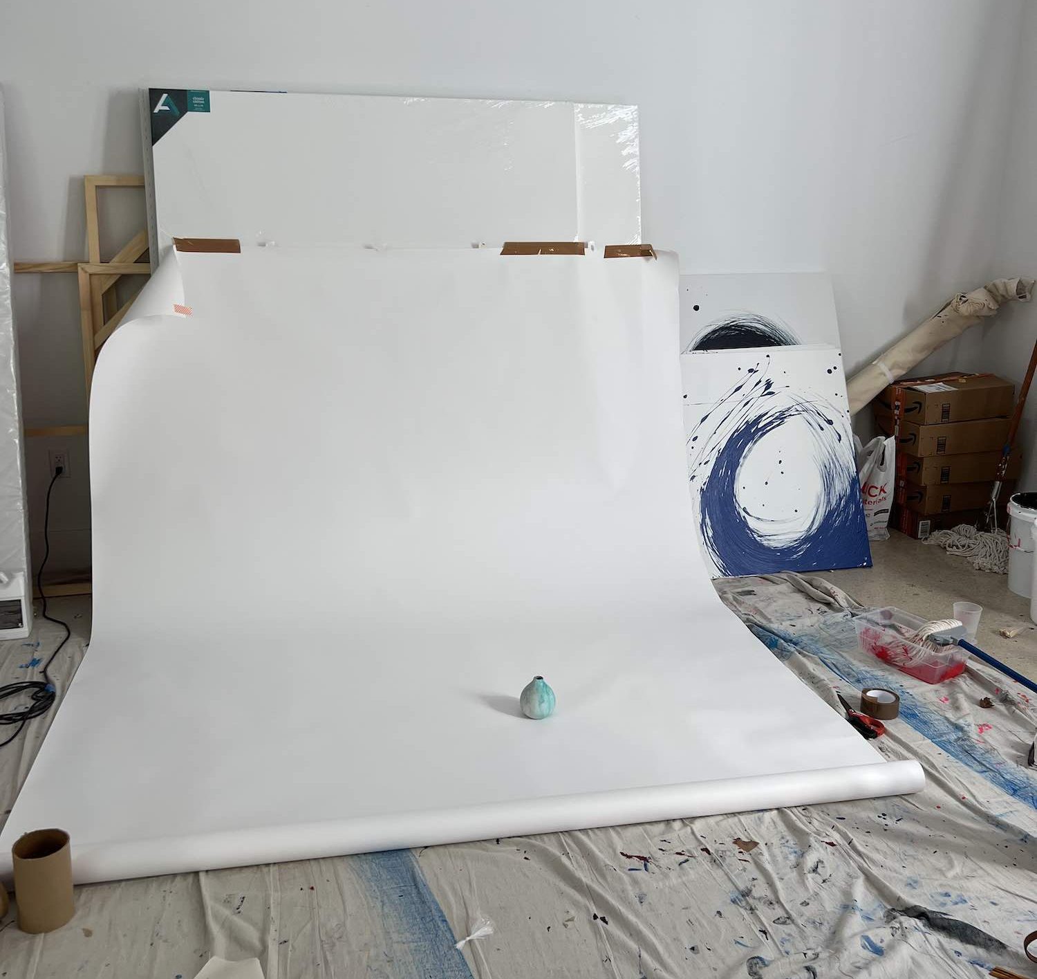 Photo of an art studio with a green vase on white paper