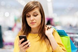 Photo of a female shopper using a mobile phone in a physical store