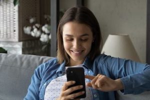 Photo of a female on a couch looking at her smartphone
