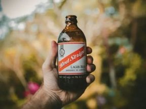 Image of a hand holding a Red Stripe lager beer. By Jakob Owens.