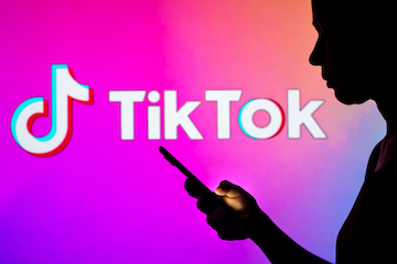 Illustration of TikTok logo next to a person holding a smartphone